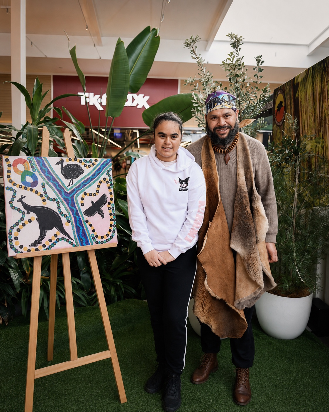 Petiola Wilson and a young woman beside displayed Indigenous artwork